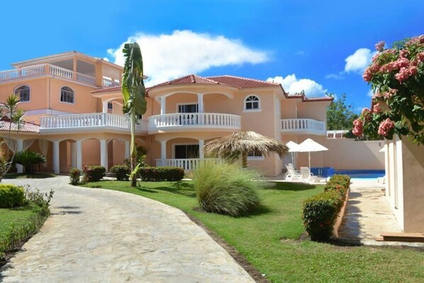 A large, multi-story building with a central courtyard, a swimming pool, and a well-maintained garden.