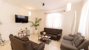 A modern living room with a flat-screen TV, two sofas, a coffee table, and a potted plant. - Private 6 Bedroom Villa Great for Parties (Sosúa)