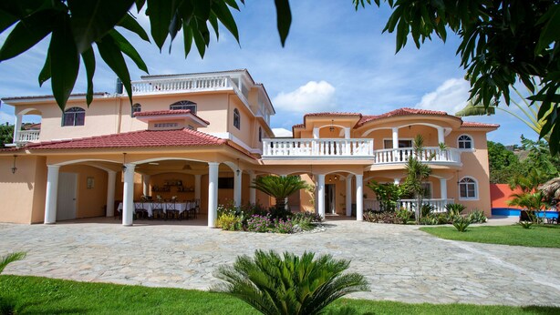 A large, two-story building with a courtyard, columns, and a tiled roof. - Private 6 Bedroom Villa Great for Parties (Sosúa)