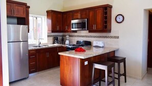 A kitchen with wooden cabinets, a stainless steel refrigerator, a microwave, a stove, and a sink. - Ocean View 2 Bedroom Villa Newly Build in Gated Community (Sosúa)