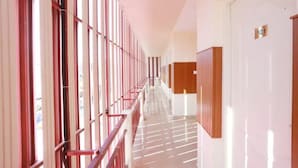 A long, narrow hallway with a series of doors on one side and a row of windows on the other. - Noor Kitchenette Residency (Kanayannur)