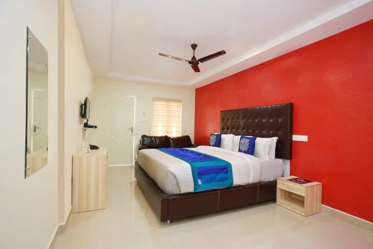 A bedroom with a bed, a ceiling fan, a TV, and a small bedside table.