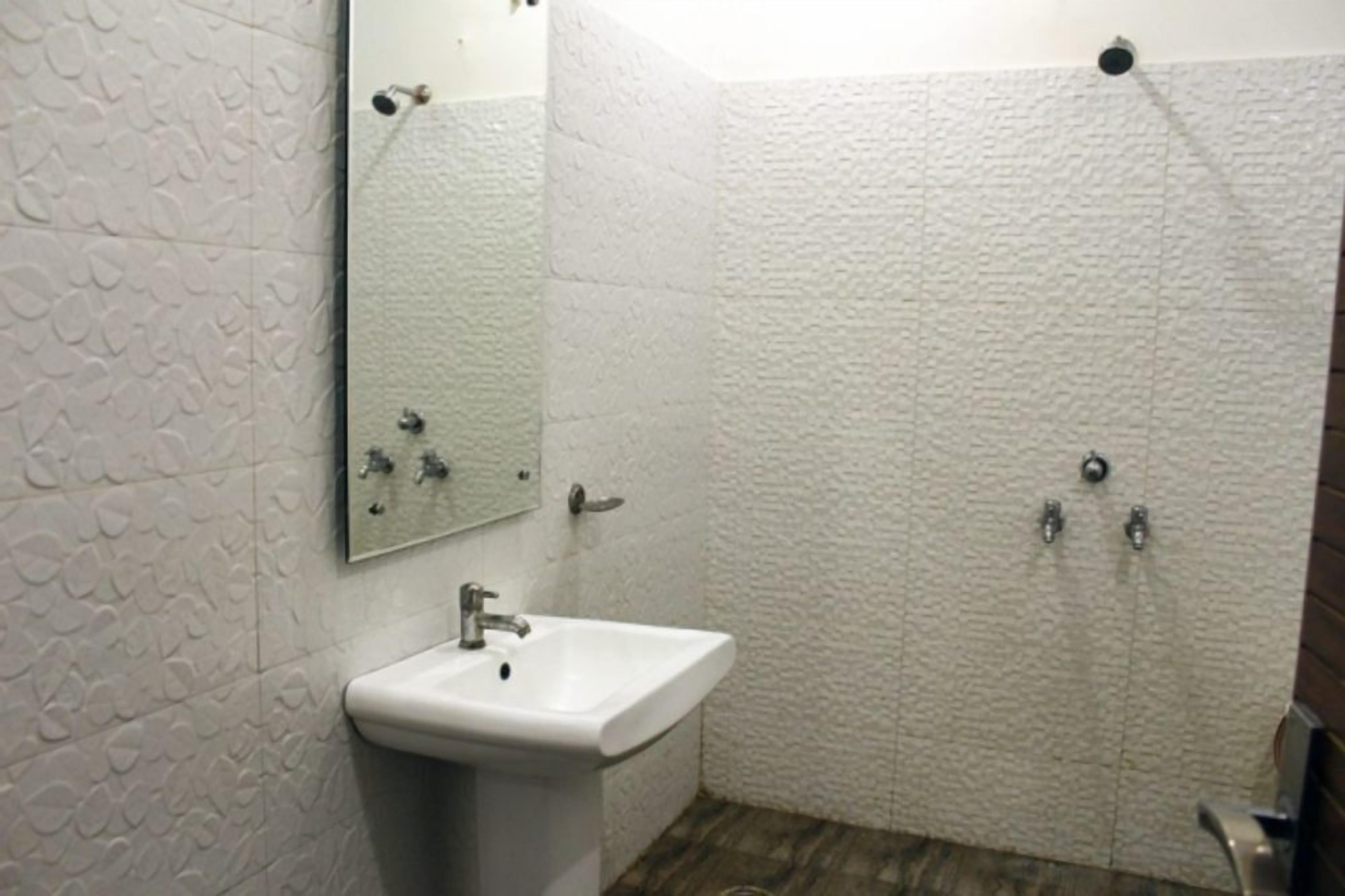 A bathroom with a white textured wall, a sink, and a shower.