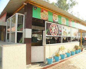 A food kiosk with a green awning displaying various food items.