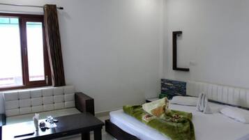 Habitación de hotel con cama, una mesita, un sofá, ventana con cortinas y un espejo en la pared.