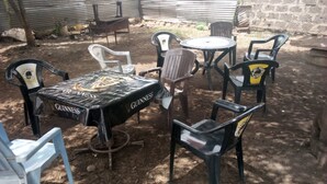 Un área de estar al aire libre con una mesa redonda y sillas, algunas cubiertas con un mantel de Guinness.
