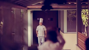 Un xef amb uniforme blanca caminant cap a una porta.