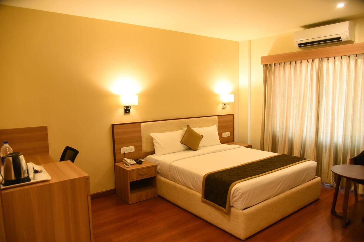 A hotel room with a large bed, bedside tables, a desk, and a chair.