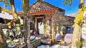 A stone building with a wooden porch, a bicycle, and outdoor seating.