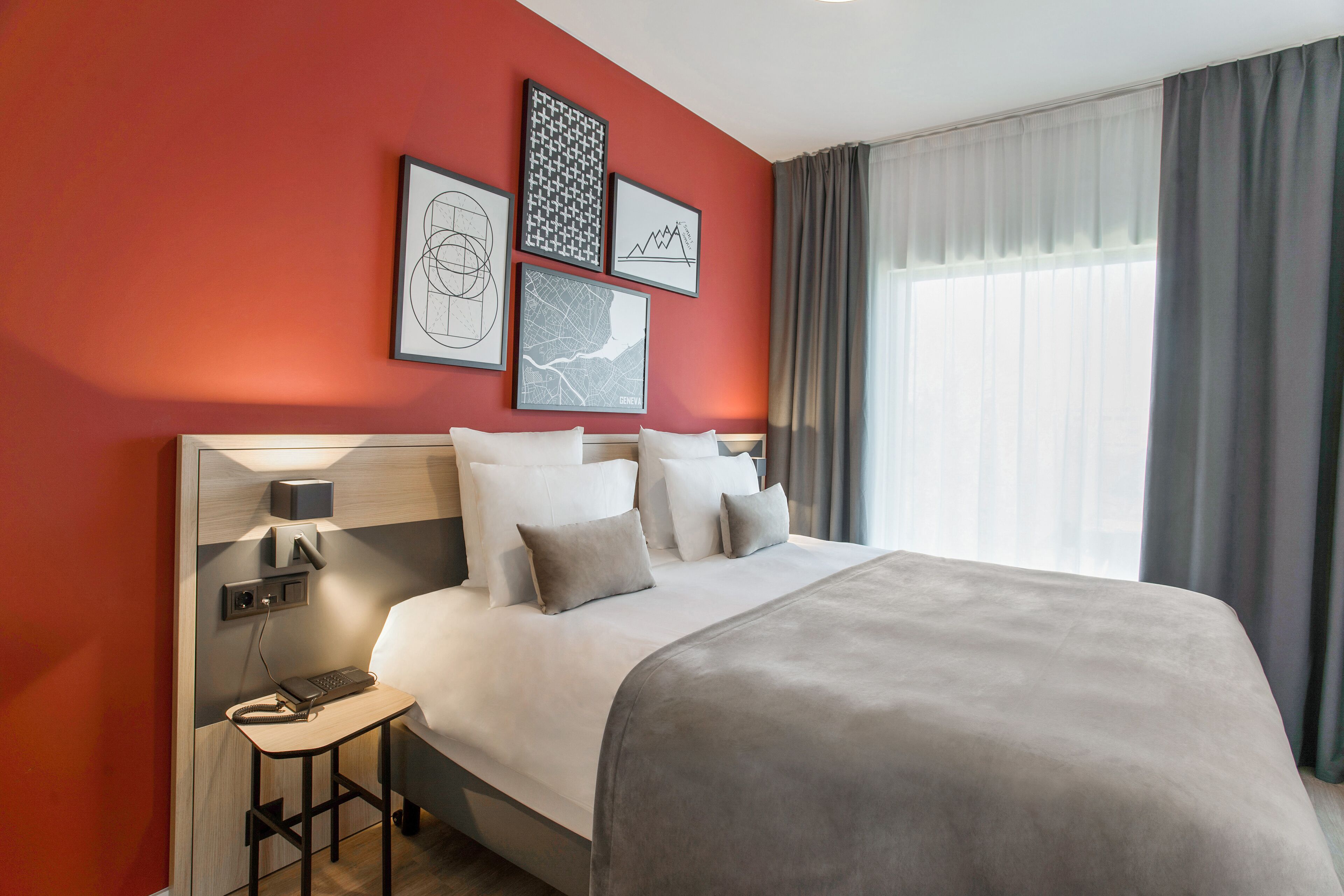 Habitación de hotel con una cama grande, una mesita de noche con teléfono y una obra de arte en la pared.