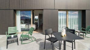 A modern outdoor patio with a table and chairs, a glass door leading to an interior room, and a view of mountains in the background. - Appart'City Collection Genève Aéroport Vernier (Vernier)