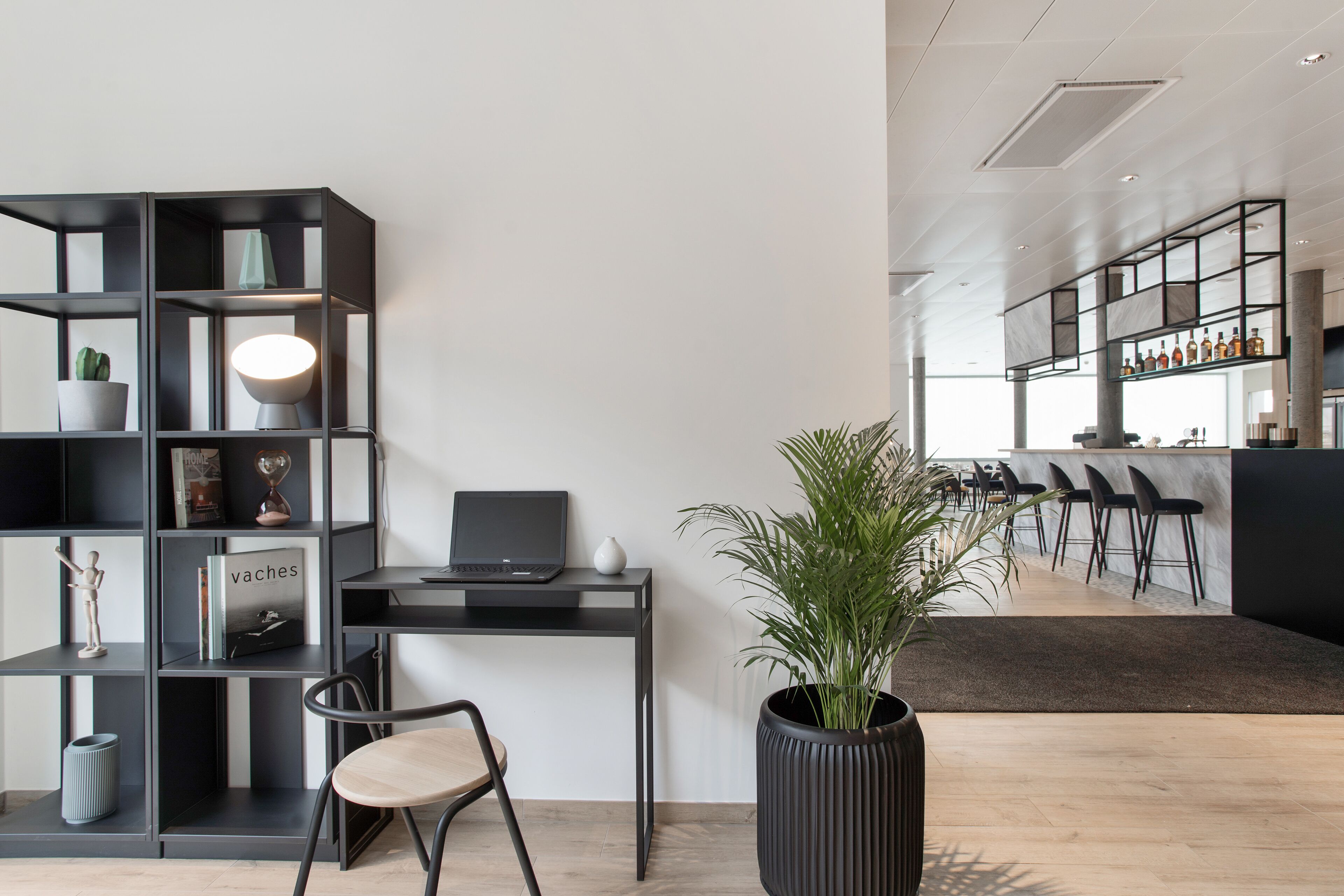 Un espacio de oficina moderno con escritorio, silla, estantería y planta en maceta.