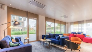 A modern living room with a blue sofa, orange armchair, and a small coffee table. - Appart'City Collection Genève Aéroport Vernier (Vernier)