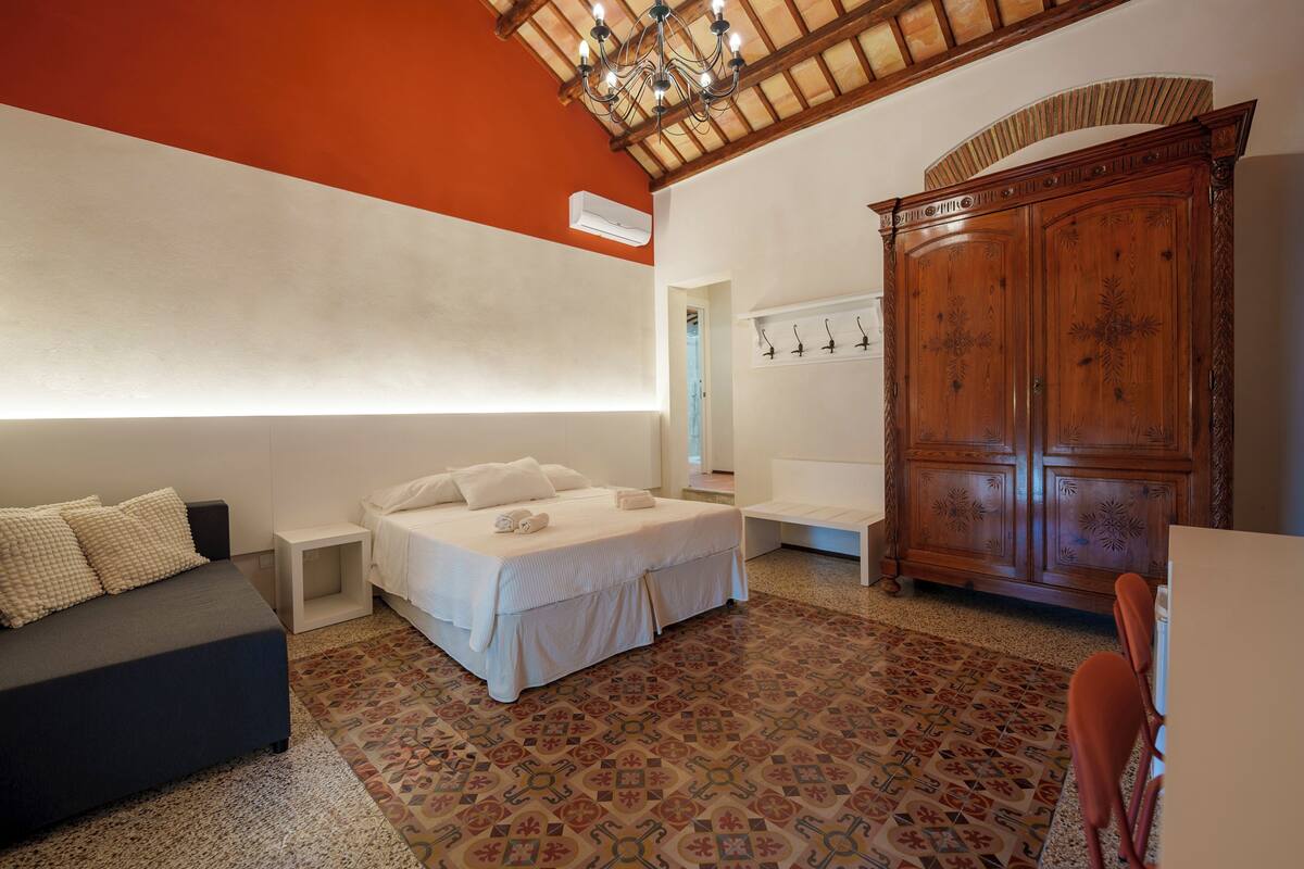 Een slaapkamer met een bed, een bank, een houten garderobe en een vloer met een patroon.