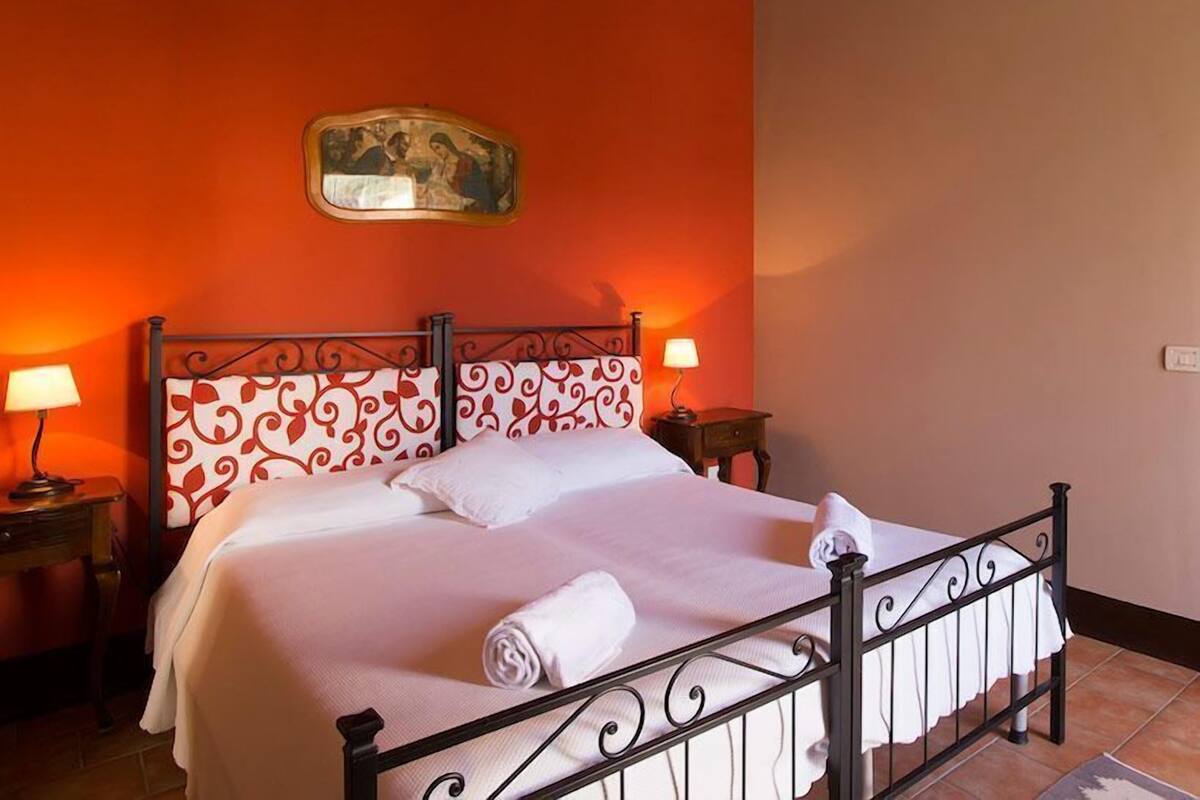 Hotelkamer met een bed, twee bedlampen, een wandairconditioner en een decoratief wandobject.