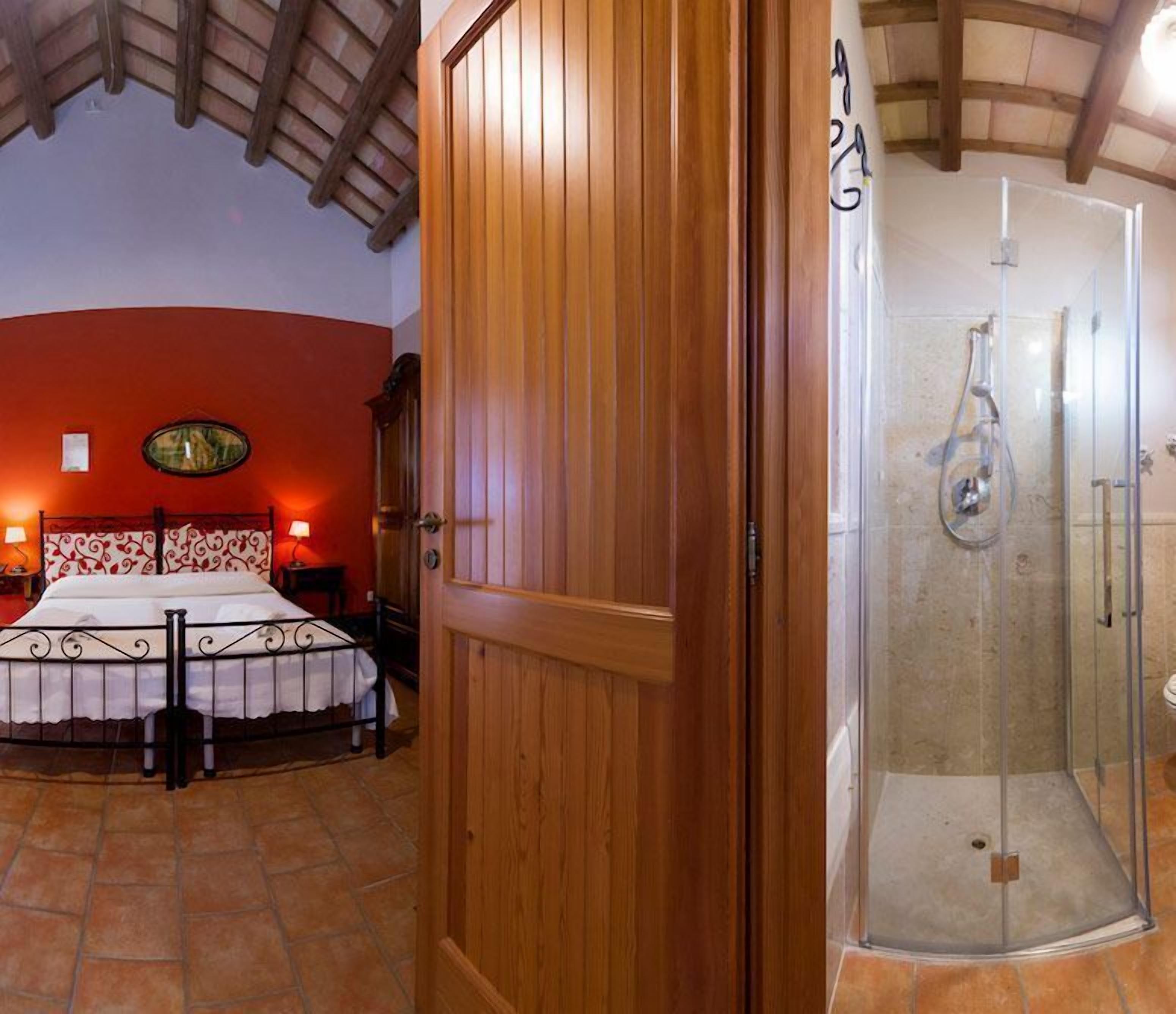 A bedroom with a bed, a wooden door, and a shower area.