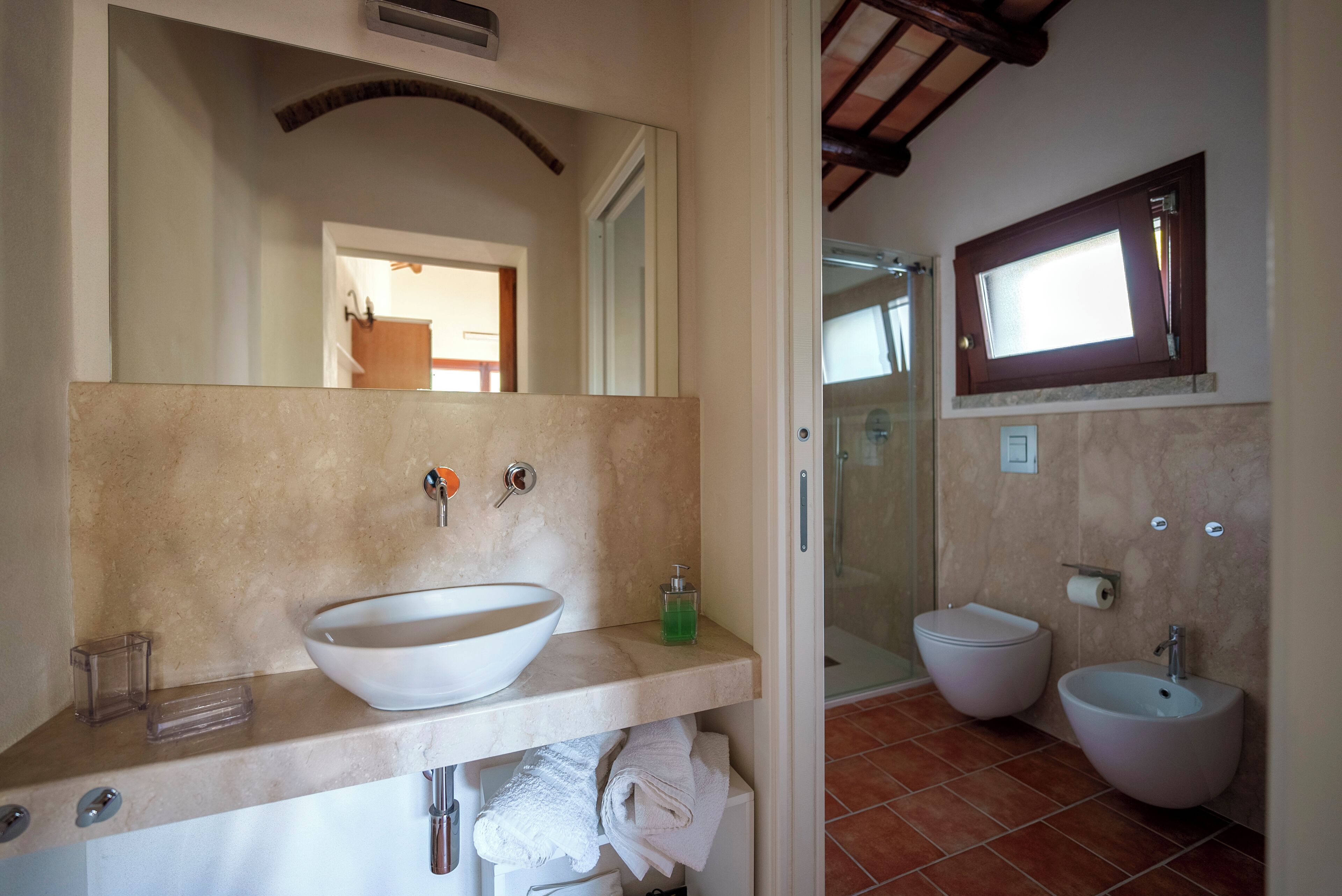 A bathroom with a large white sink, a mirror, a shower, and a toilet.
