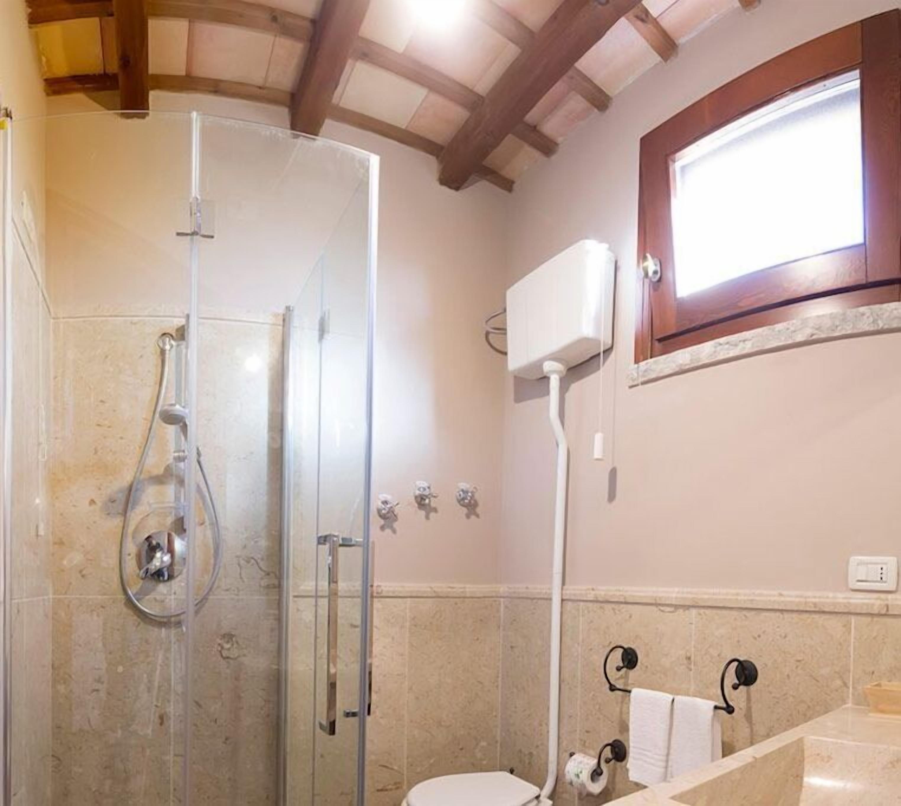 A bathroom with a glass shower enclosure, a toilet, and a sink.
