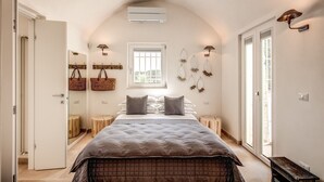 A bedroom with a large bed, a window, and a door.