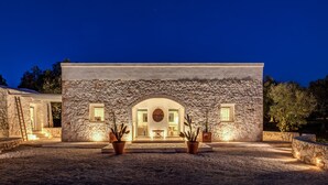 A stone building with an arched entrance, potted plants, and a gravel driveway.