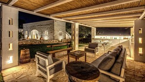 An outdoor patio area with stone flooring, wooden furniture, and a stone wall.