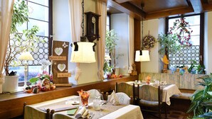 Un coin repas chaleureux, avec des meubles en bois, des nappes blanches et diverses plantes.