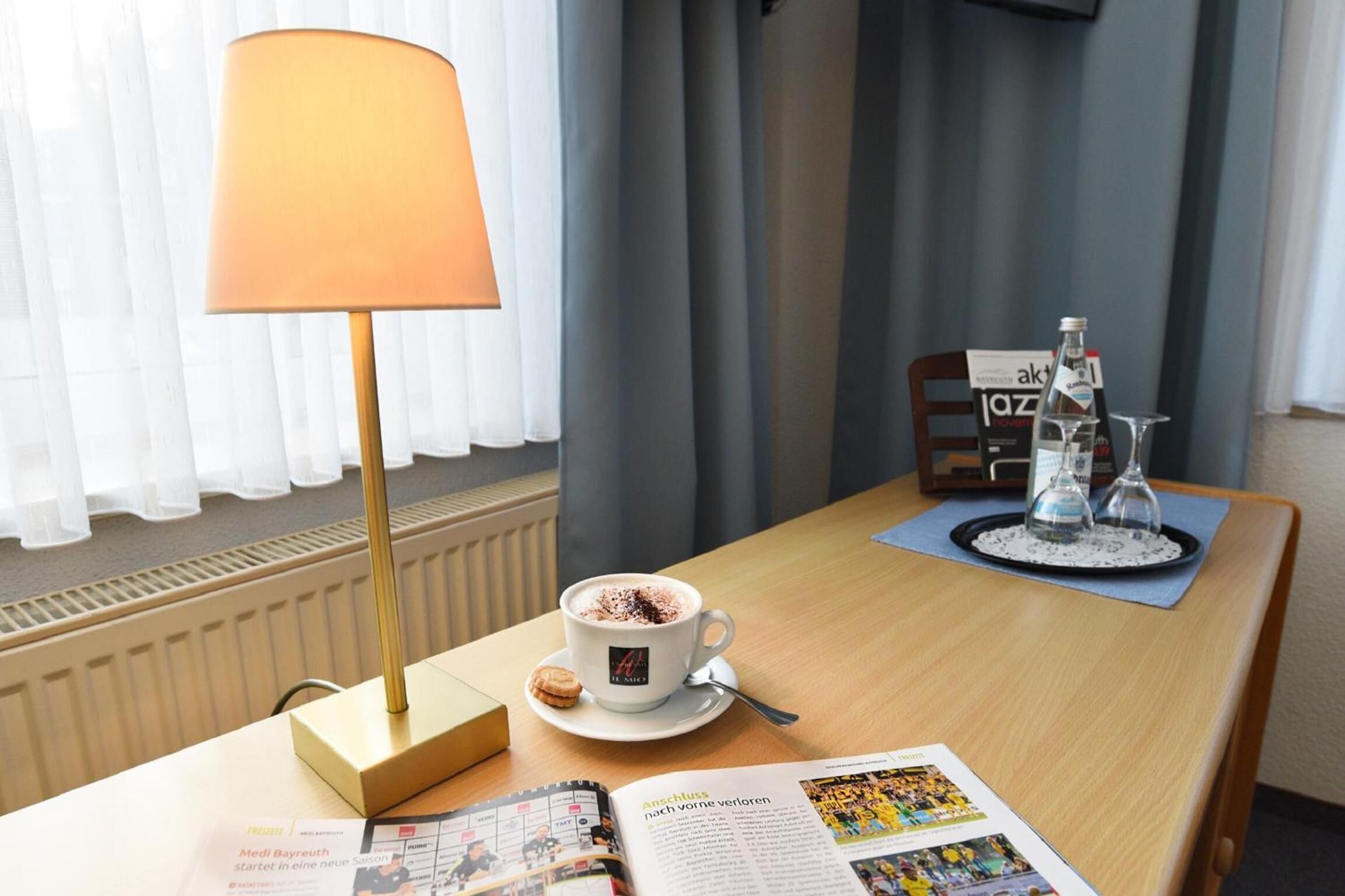 A hotel room with a table set for breakfast, including a cup of coffee, a glass of water, and a menu.