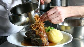 Ein Koch bereitet ein Gericht mit Fleisch und Dekoration zu.