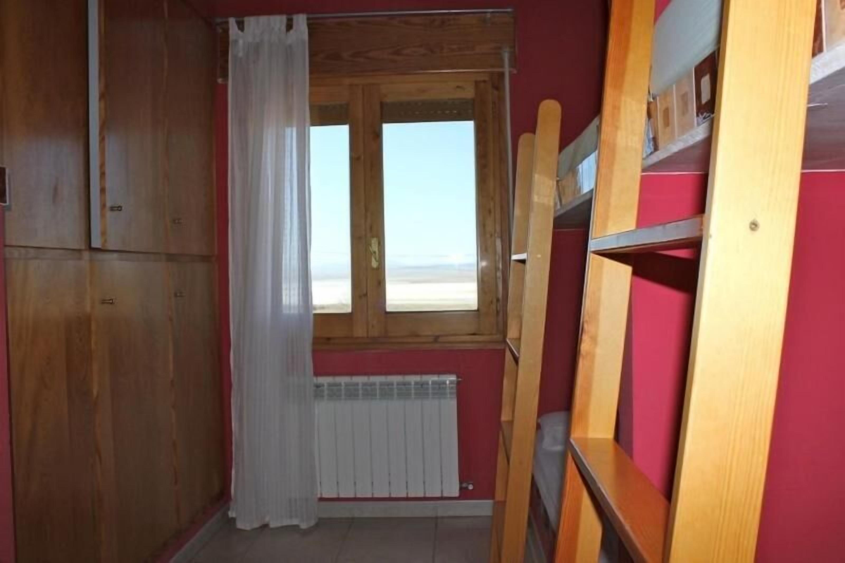 Una habitación con literas, un armario de madera y una ventana con vistas.