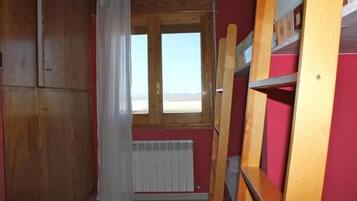 Una habitación con literas, un armario de madera y una ventana con vistas.