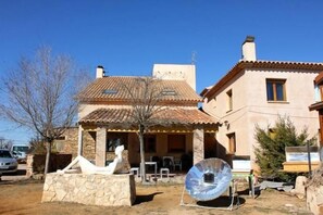 A two-story house with a tiled roof, a stone patio, and a satellite dish.