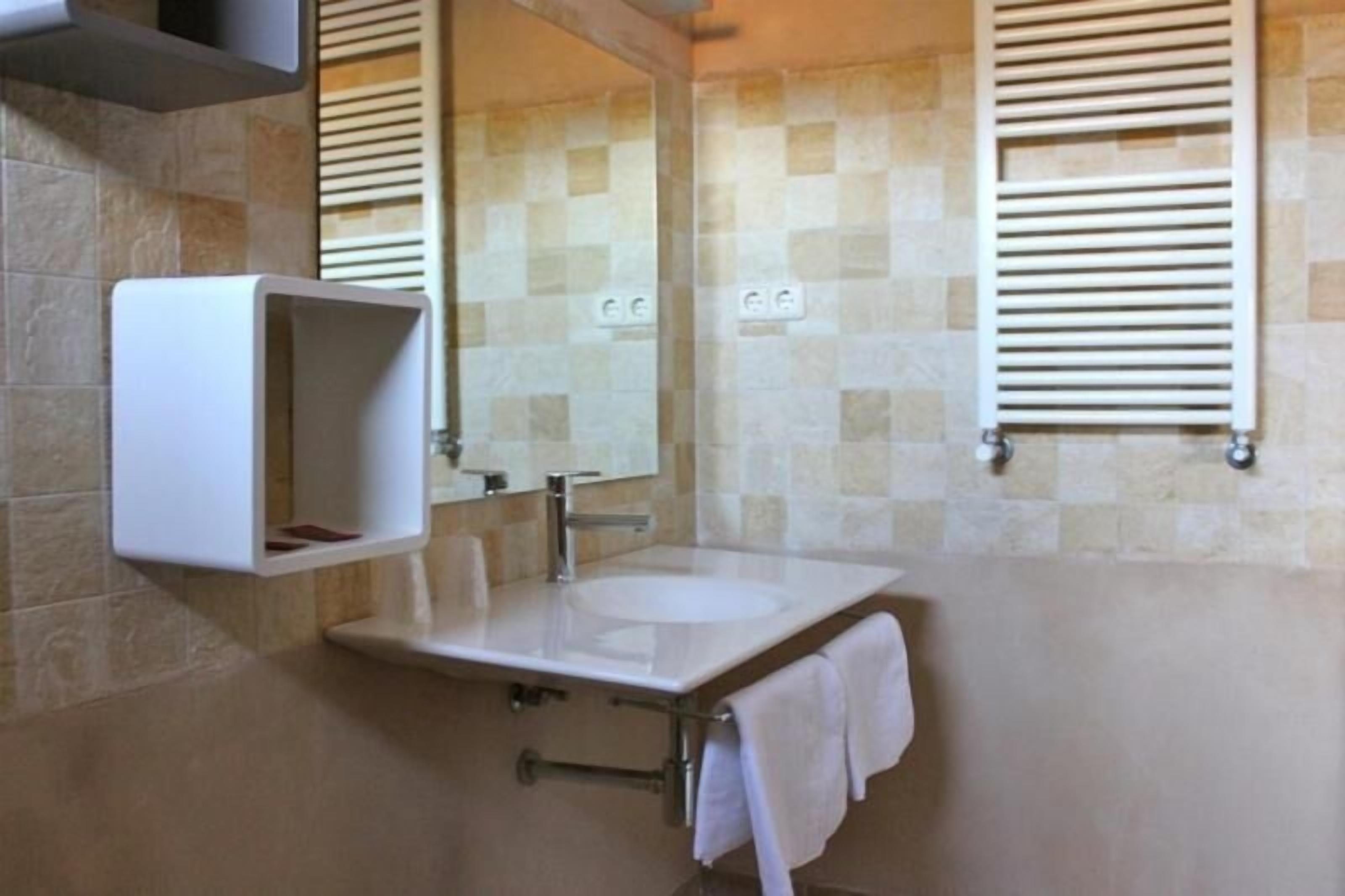 A bathroom with a white sink, a mirror, and a towel rack.