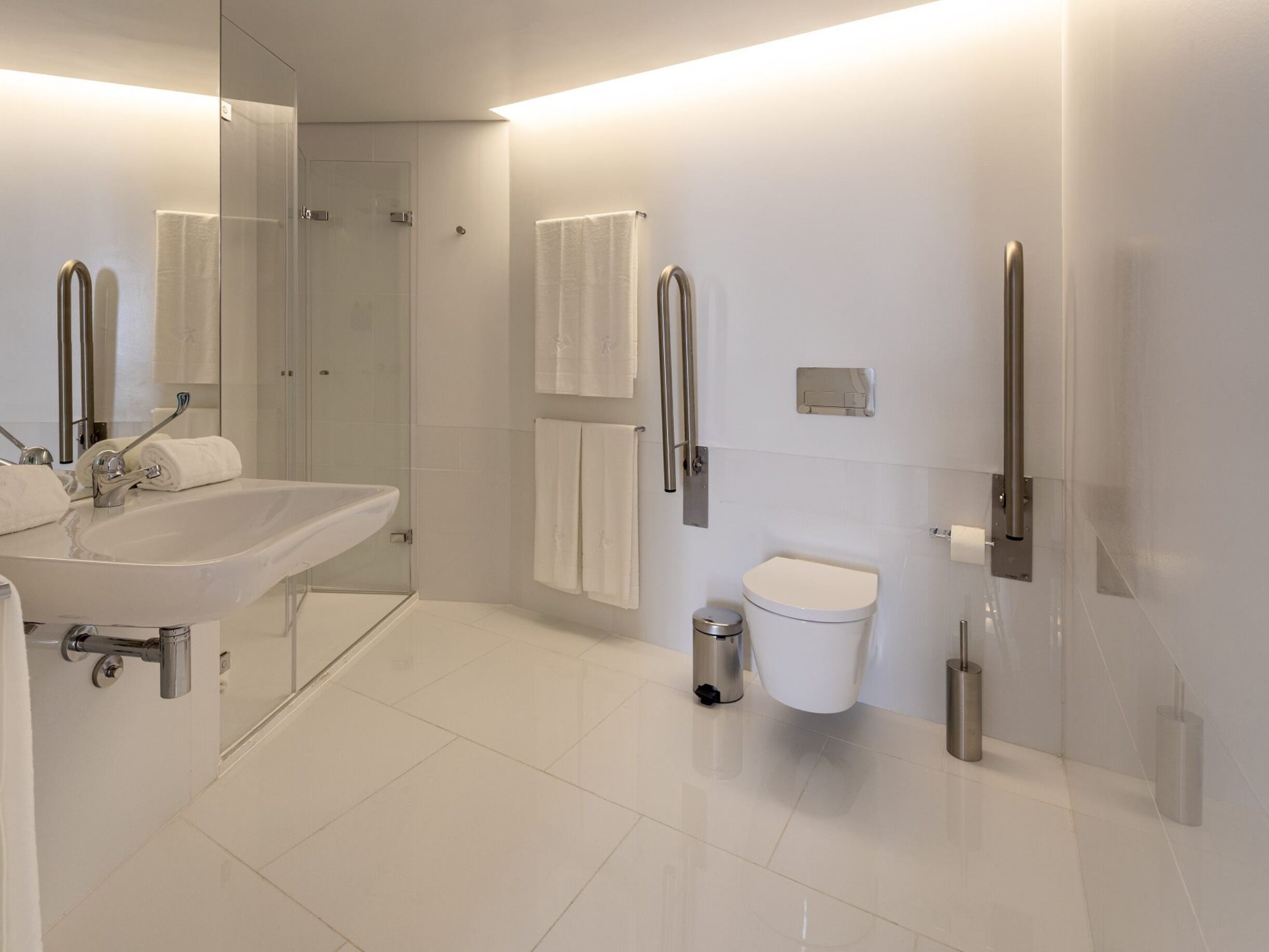 Une salle de bain moderne équipée d’un lavabo, de toilettes et d’une zone douche.