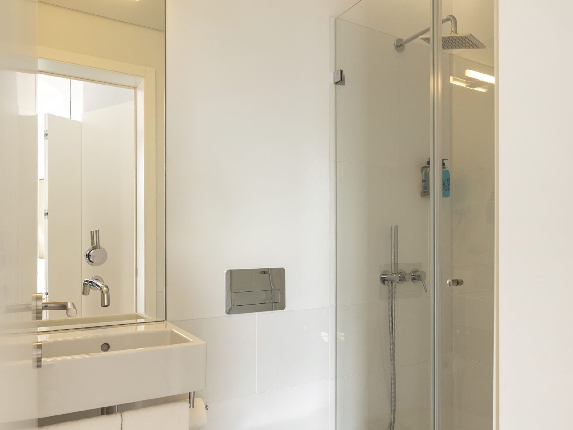 Un bagno con specchio, lavandino e doccia.
