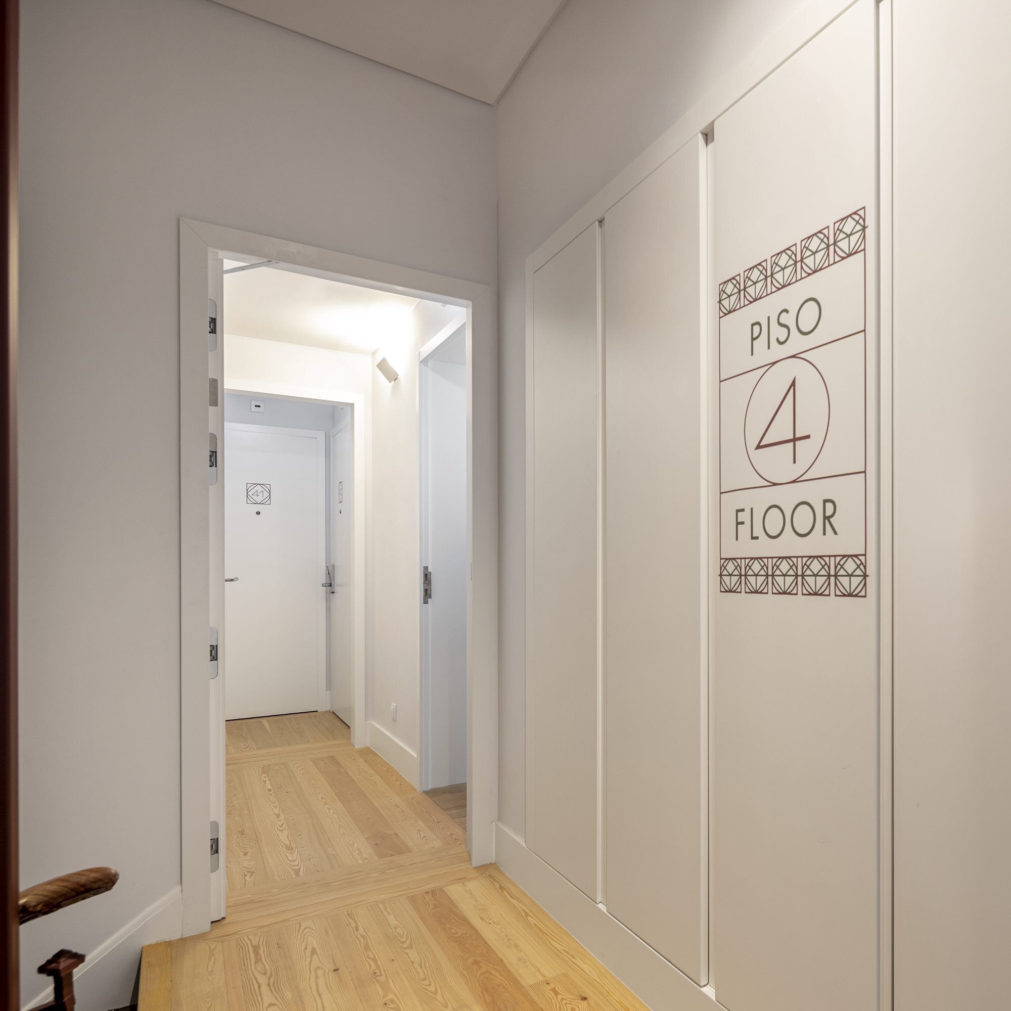Un pasillo con suelo de madera, una puerta blanca y una pared con un letrero que indica 'PISO 4 FLOOR'.