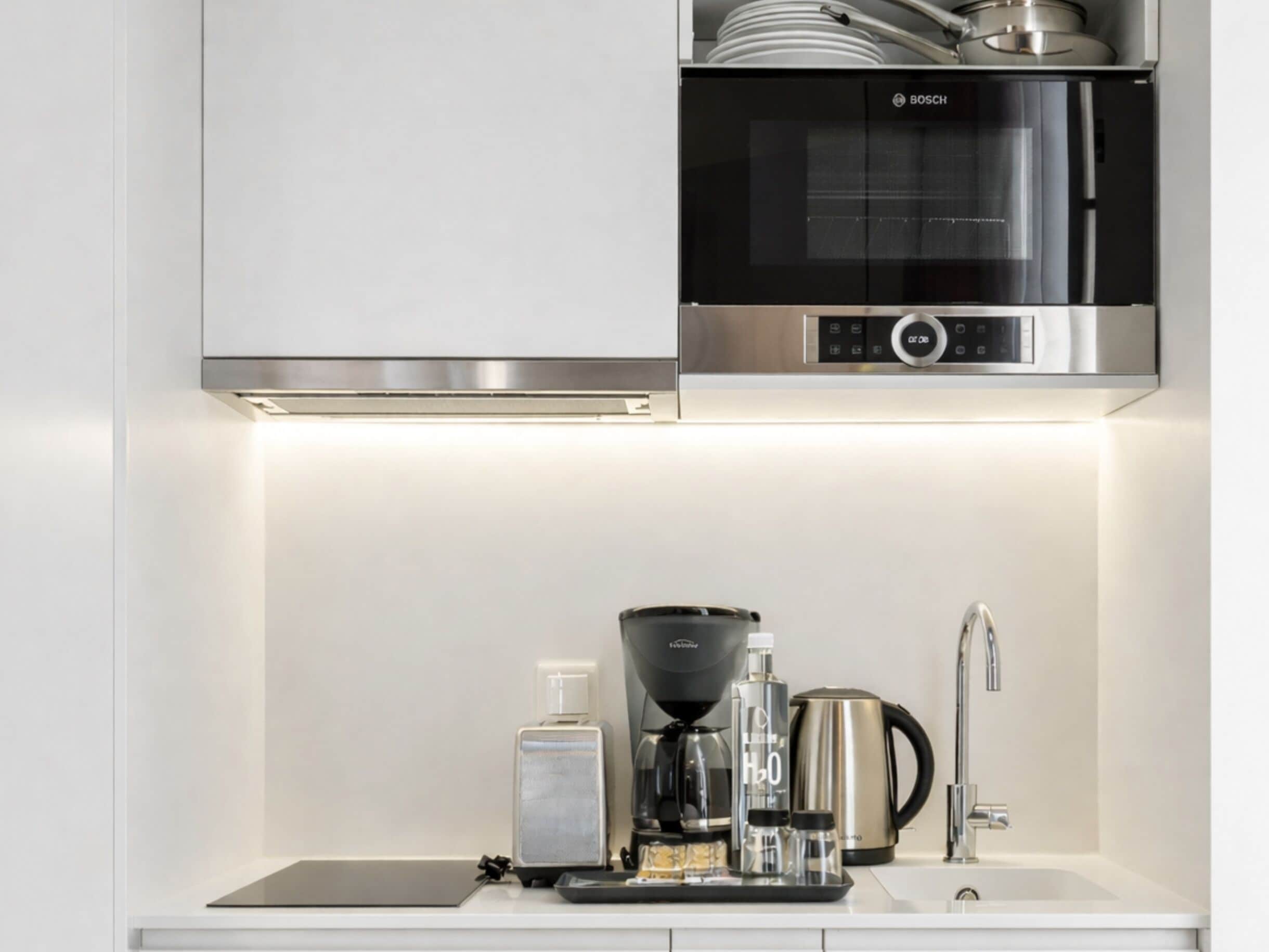 A kitchen with a Bosch microwave, a coffee maker, and a kettle on the counter.