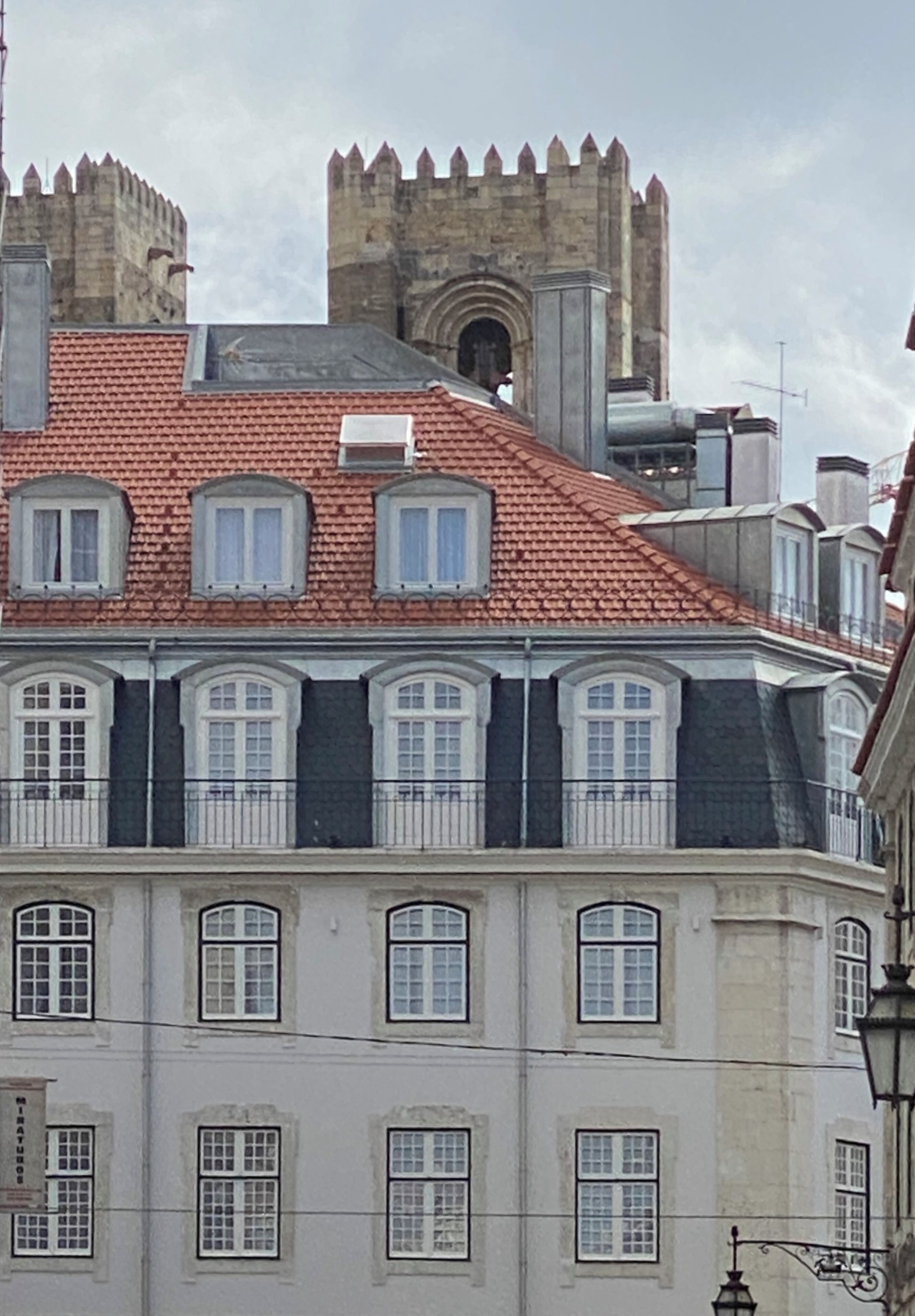 Ein Gebäude mit rotem Ziegeldach, zahlreichen Fenstern und einem hohen Turm mit Zinnen.