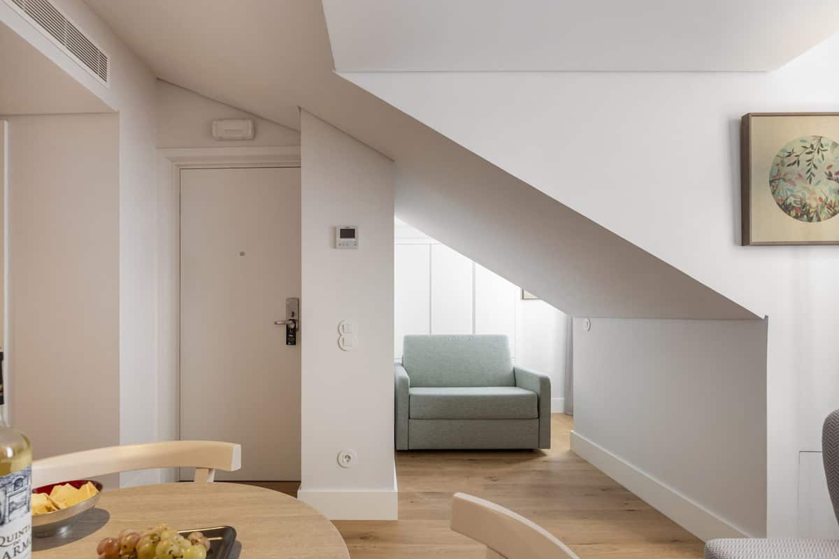 A modern interior with a dining area, a sofa, and a staircase leading to another room.