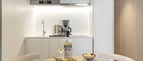 Una cocina compacta con un microondas Bosch, una cafetera y una botella de vino Quinta Carmo sobre la encimera.