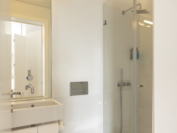 Un baño con lavamanos, espejo y cabina de ducha de vidrio.
