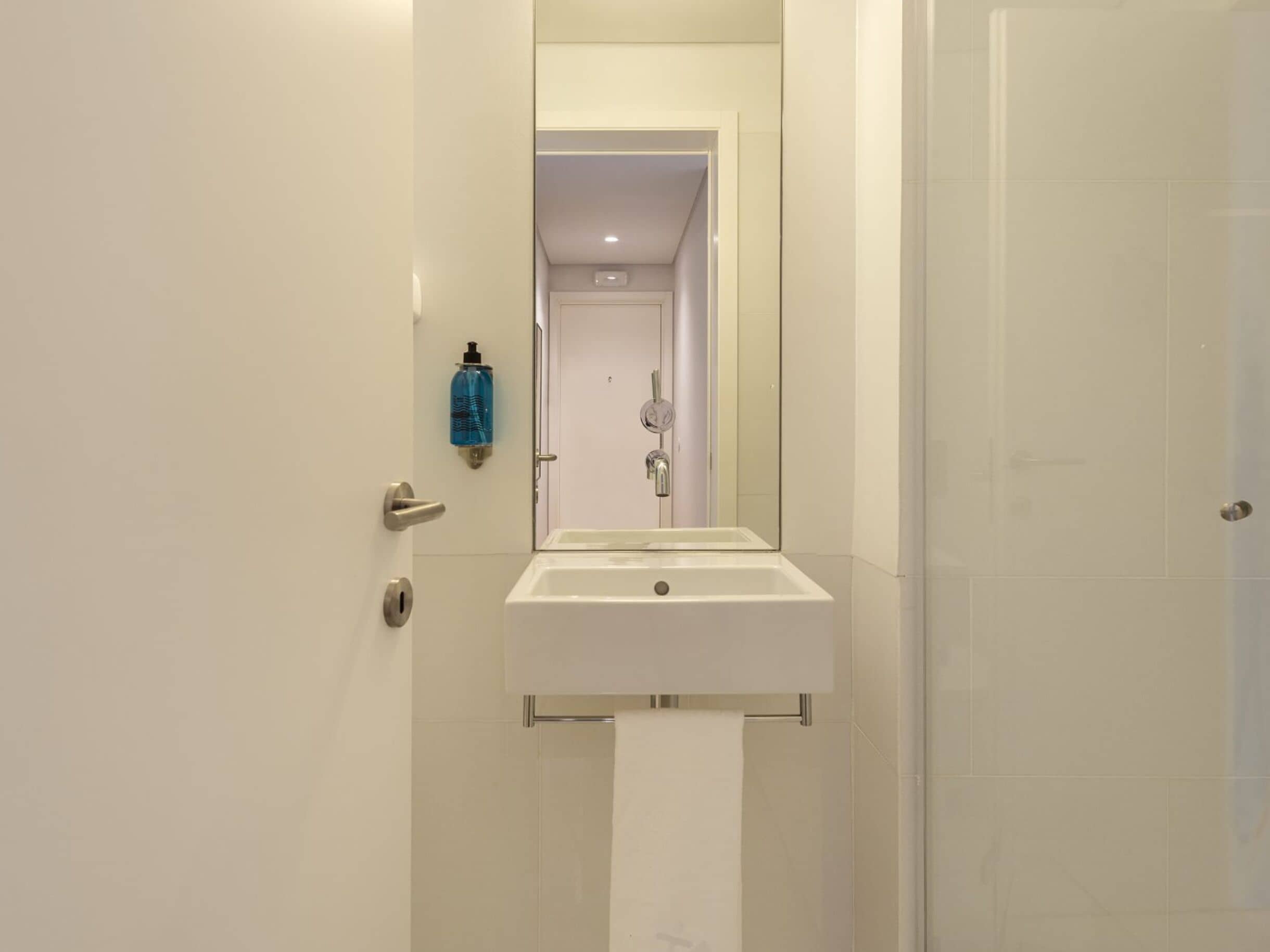 Un baño con un lavabo blanco, un espejo y una puerta.