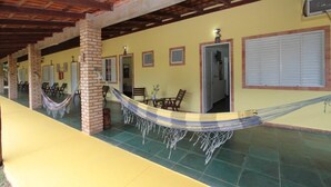 Un espacio al aire libre techado con pilares de ladrillo, una hamaca y suelo de baldosas.
