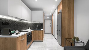Eine moderne Küche mit Holzschränken, einer schwarzen Küchenfliese als Rückwand und einem eingebauten Backofen.