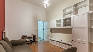 En moderne stue med sofa, spisebord med stole og hvide indbyggede skabe.