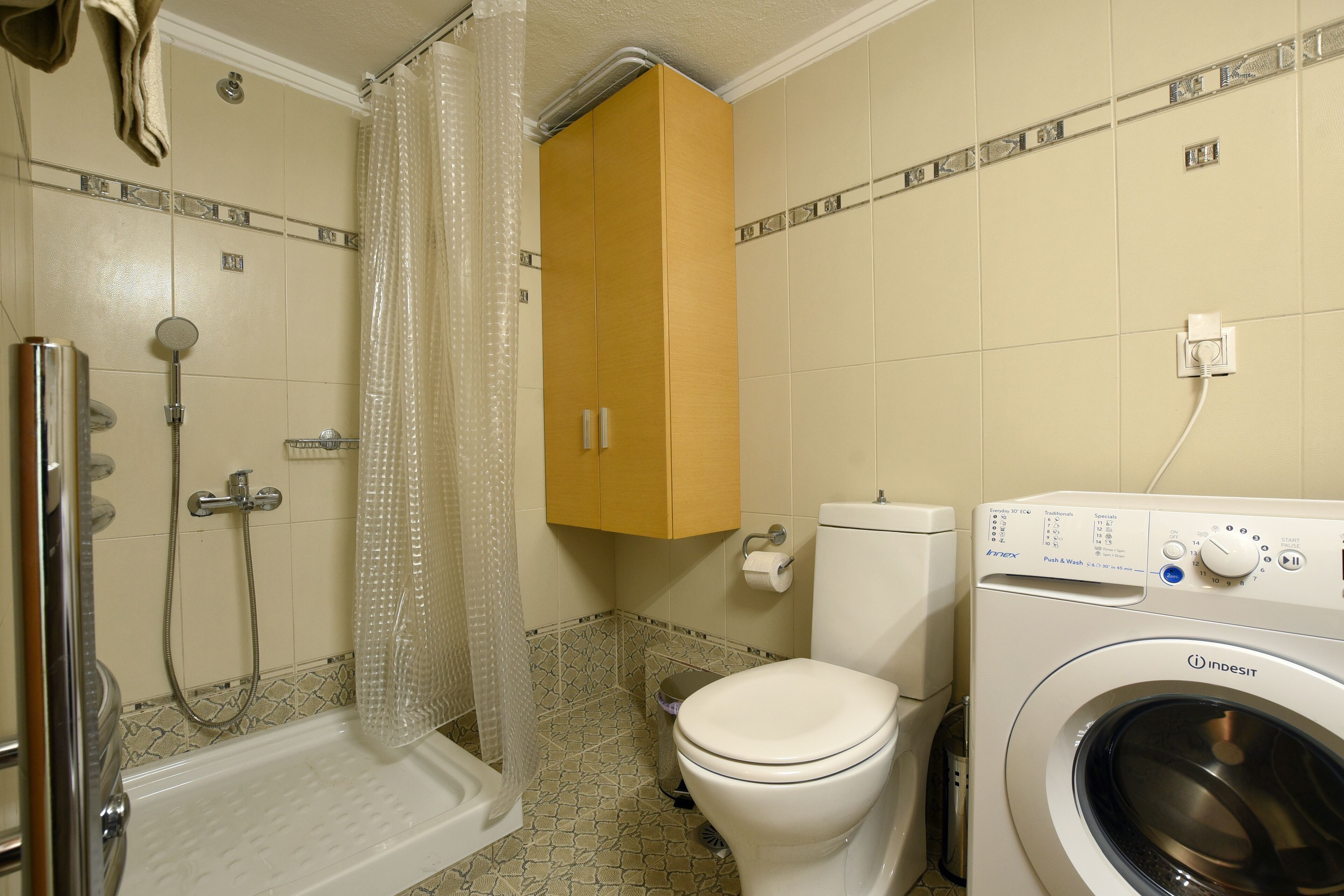 Ein Badezimmer mit Dusche, Toilette und Waschmaschine.