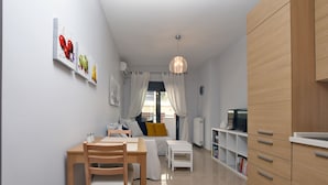 Une cuisine moderne avec des meubles en bois, un coin repas avec une table et des chaises, et un espace de vie avec un canapé et un téléviseur.