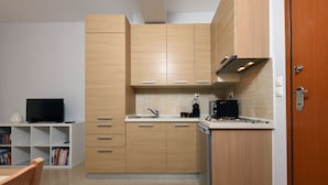 Une cuisine compacte avec des meubles de rangement en bois, un lave-vaisselle encastré et un petit plan de travail.