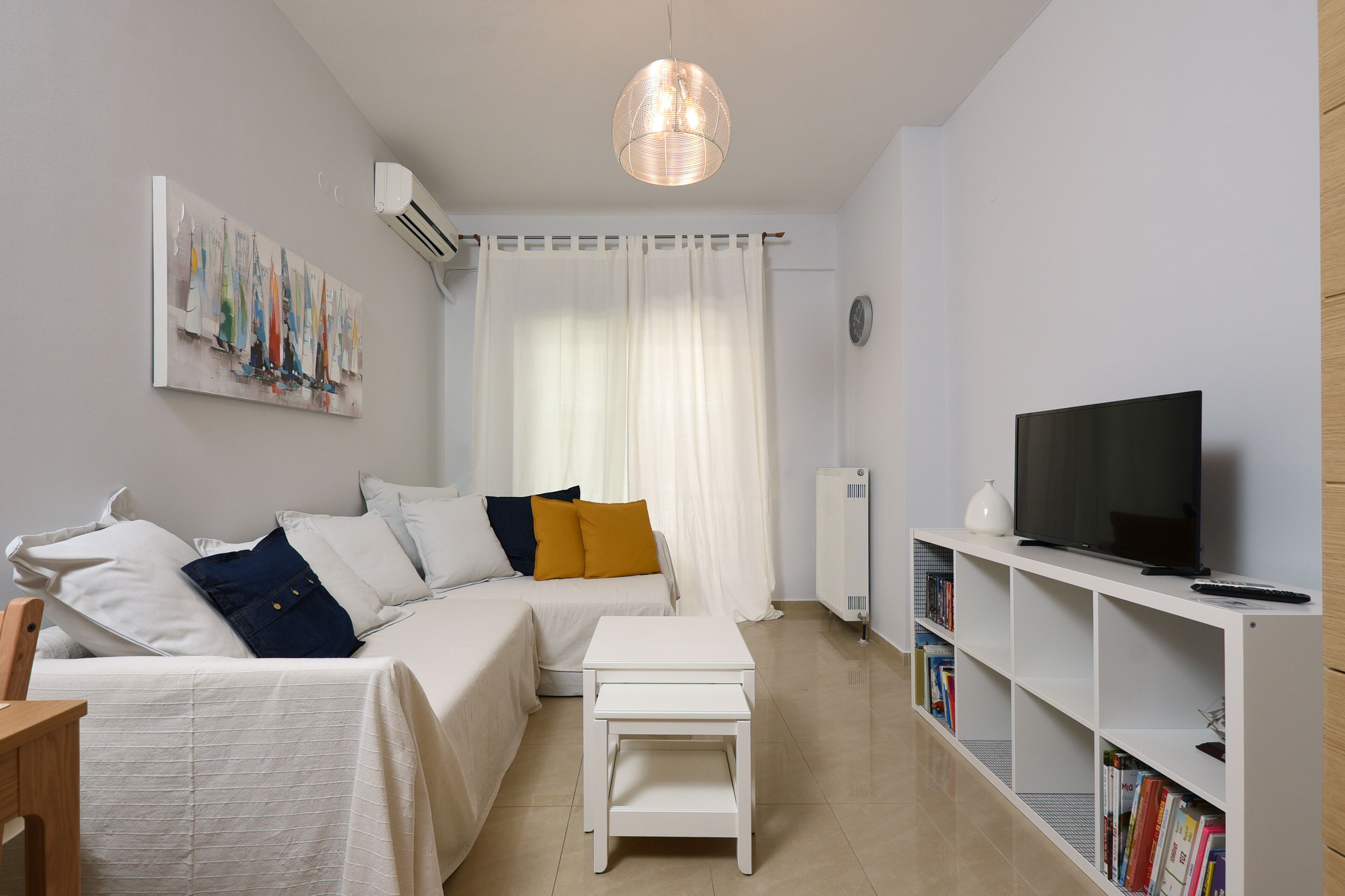 A modern living room with a sofa, a coffee table, a TV, and a bookshelf.