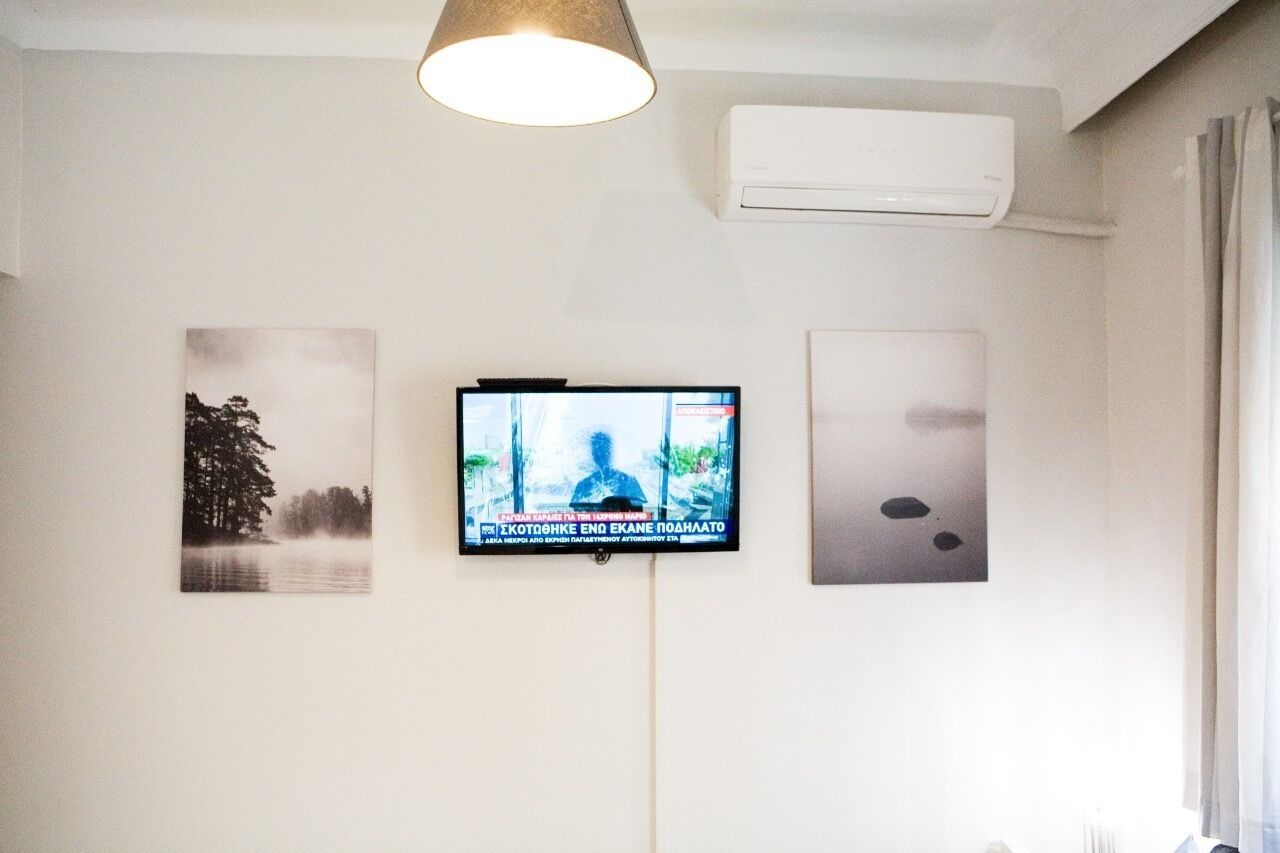 Une pièce équipée d’un téléviseur fixé au mur, d’un climatiseur mural et de deux tableaux encadrés.