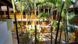 A courtyard with a central garden, surrounded by yellow buildings with balconies. - Pousada A Cor do Sol (Ubatuba)